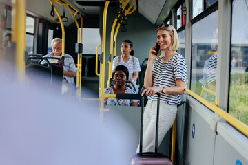 Young woman with suitcase talking on phone in shuttle bus