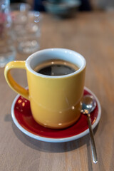 a yellow mug morning coffee on a red saucer on the table