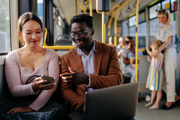 Asian woman showing black man cellphone on bus