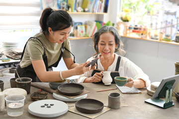 Female craft pottery shop owner taking photo of product for upload to website online shop. Online selling, E-commerce concept