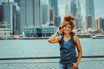 Portrait beautiful young adult woman afro hairstyle with Manhattan New York City skyline in the background outdoors shot