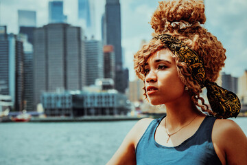 headshot beautiful young adult woman afro hairstyle with Manhattan New York City skyline in the background outdoors shot