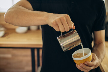 Barista pours milk into a cup with cappuccino