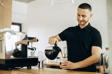 Barista at a coffee house pouring coffee in a glass