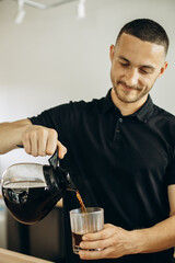 Barista at a coffee house pouring coffee in a glass