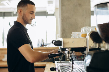 Man barista at coffe shop preparing coffee in a coffee machine