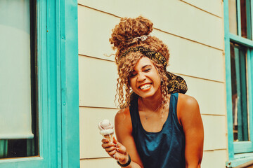 young adult woman afro hair smiling eating ice cream outdoors summertime shot