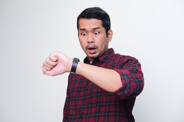 Adult Asian man showing shocked expression when looking to his watch