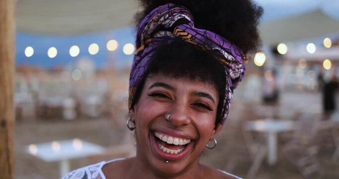 Bohemian african girl smiling on camera with beach bar on background 