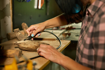 Female using power wood working tools graver, carving while crafting