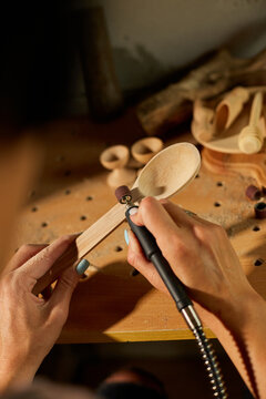 Female using power working tools graver for wooden utensils spoon
