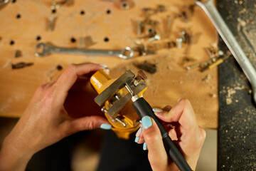 Woman using power working grinder machine, female hand grinds a metal nuts