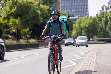 Fototapeta na wymiar Courier On Bike Delivering Takeaway Food In City