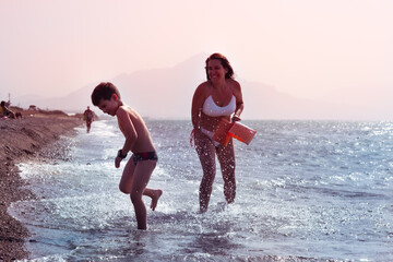 mum and son in the coast play at the beach smiling