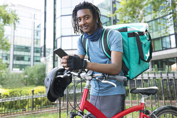 Portrait Of Corurier On Bike Delivering Takeaway Food Using Mobile Phone