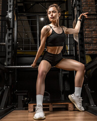Fototapeta na wymiar Athletic girl with a beautiful figure in the gym