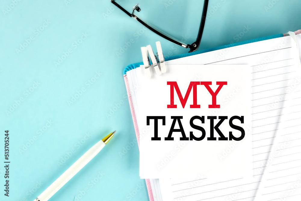 Poster my tasks text on a sticky on notebook with pen and glasses , blue background