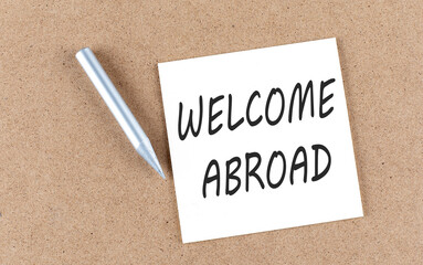 WELCOME ABROAD text on sticky note on a cork board with pencil ,