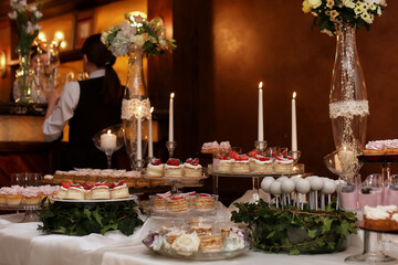 festive table with sweets and a variety of sweet snacks against the backdrop of  a girl confectioner