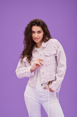 Portrait of young pretty girl with long wavy hair in casual suit looking at camera standing on purple background