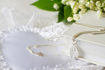 First Holy Communion with sacred medal on chain and flowers, concept background 