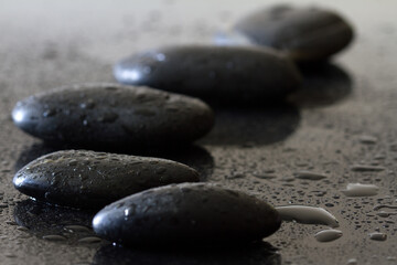 Fototapeta na wymiar Dewy stones on black background, spa concept, body and mind, zen stone