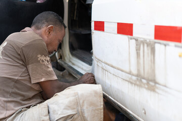 Mechanic Working On Car In Garage/Workshop