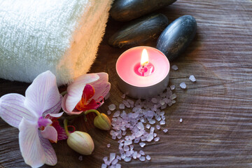 Fototapeta na wymiar Bath salt, candle, massage stones, towel and orchid on wooden background, spa concept