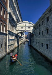 Venice, Italy - September 05, 2018: A man rowing gondola boat with passengers on a green water canal through famous bridge of sigh during day