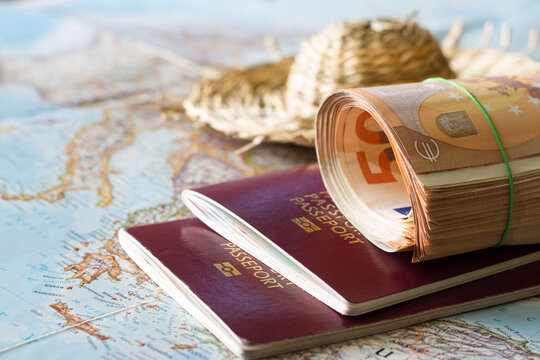 Map, passports, wad of money, and straw hat, concept of expensive vacation