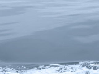 Fototapeta na wymiar Gray tone calm blue sea surface gradation texture background. Photograph taken from the running fishingboat. 曇天べた凪の海面。