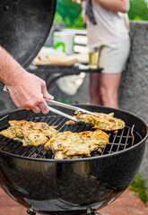 young man chef cooking chicken meat on grill outdoor