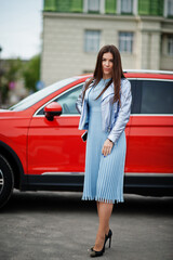 Outdoor photo of gorgeous woman posing near orange suv car.