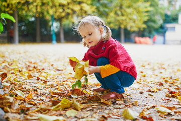 Adorable preschooler girl enjoying nice and sunny autumn day outdoors - obrazy, fototapety, plakaty