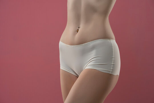 Mid section of woman wearing white briefs,  front view on a pink background