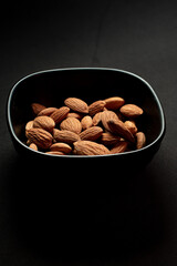 close up some almonds in bowl in dark background