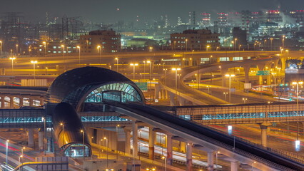 Futuristic building of Dubai metro station and big junction behind in Dubai Marina aerial night...