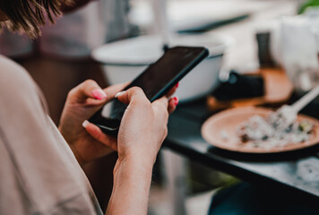 woman hand holding and using smartphone in outdoor cafe