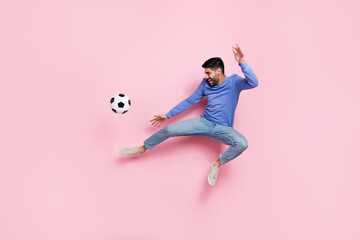 Full length photo of pretty funky man wear long sleeve shirt jumping high playing football isolated...