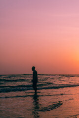 Fototapeta premium Male model walking on tropical beach at sunset, beautiful holiday landscape.