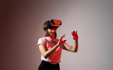 Young woman working in VR goggles on a grey background. Modern architect using virtual reality glasses at workplace. Designer working in augmented reality vr studio.