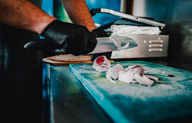 Chefs man hands chopping onion on board in kitchen