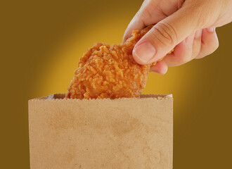 Fried chicken on this hand with paper bag of more fried chicken
