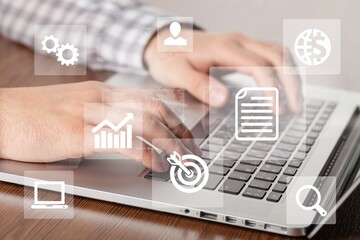 Business man working with laptop computer with icons on virtual screen on office desk.
