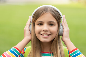 Portrait of happy girl with smiling face listening to music in headphones outdoors