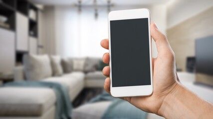 Smart home concept.  Woman holding mobile phone on home interior background. Internet of things, comfort in house