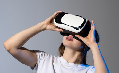 Young brunette woman wearing a virtual reality headset goggles and playing a game with a friends in metaverse. Future technology concept.