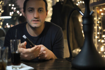 man smoking pipe of hookah in night cafe