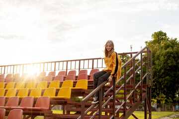 Fototapeta na wymiar A teenage girl has fun and slides down the railing at the stadium