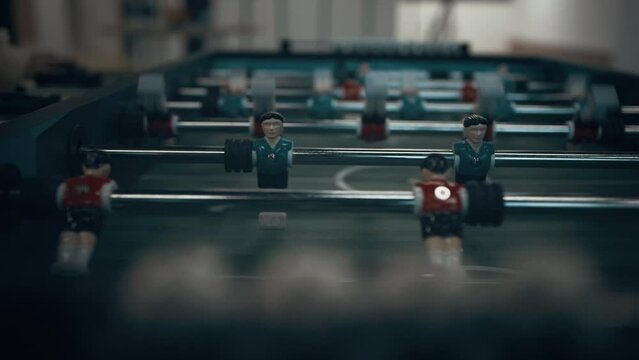 Closeup miniature plastic figures on football table. Children hands revolve rods